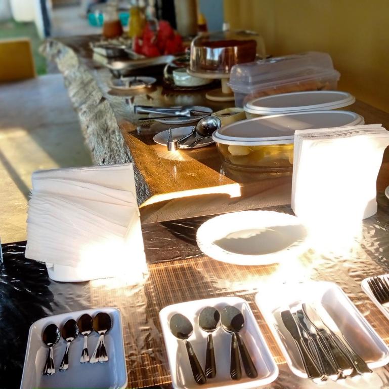 a long table with plates and utensils on it at Pousada Diadorim in Sao Domingos de Goias