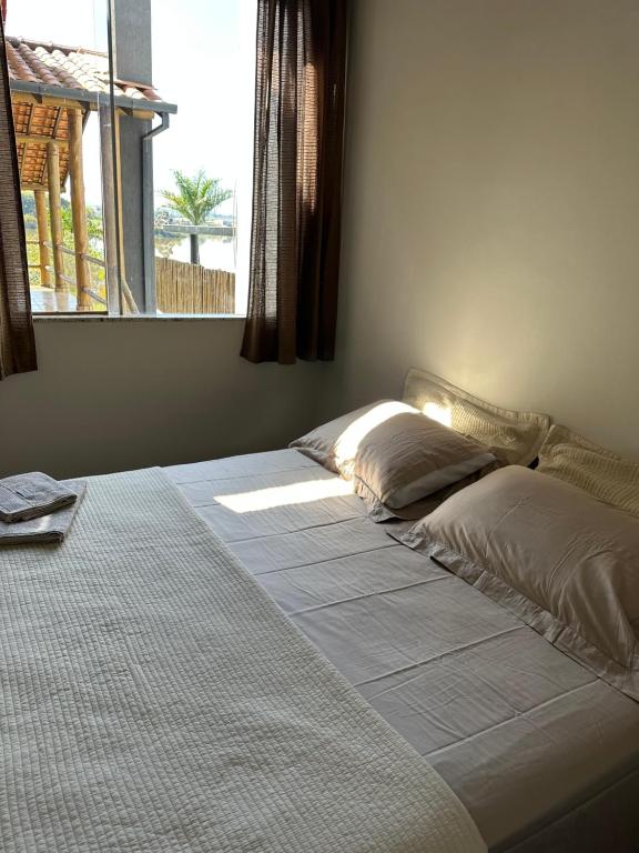 a bed with two pillows in a bedroom with a window at Casa no Condomínio Naútico Porto da Pedra em Ijaci in Macaia