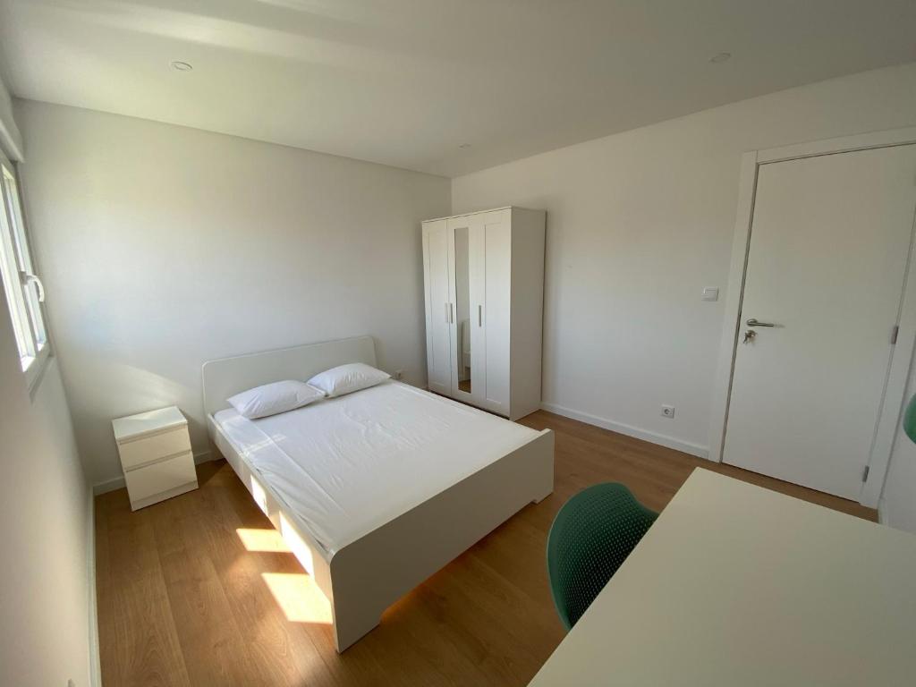 a white bedroom with a bed and a chair at Carcavelos Beach Walking distance room in Oeiras