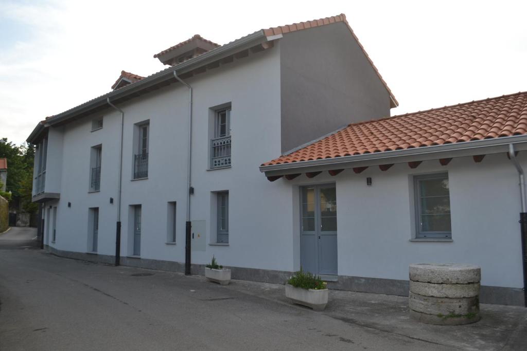 a white building with a red roof on a street at El Molino 3 in Muros de Nalón