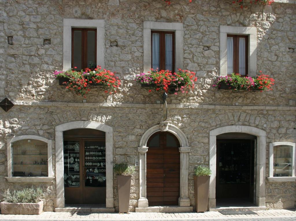 a stone building with flower boxes on the windows at Affittacamere Prato Rosso in Pescasseroli