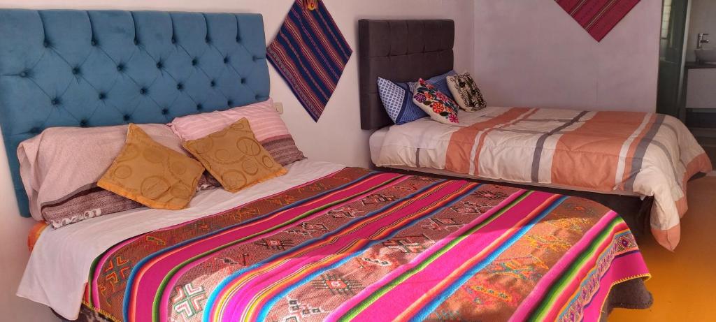 a bedroom with two beds and a blue headboard at Uros TITICACA home lodge in Puno