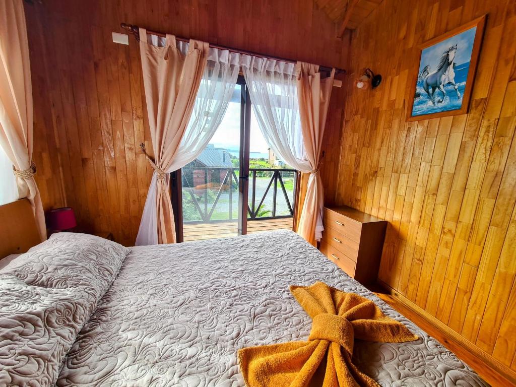 Un dormitorio con una cama y una ventana grande. en Cabañas Kompatzki, en Ancud