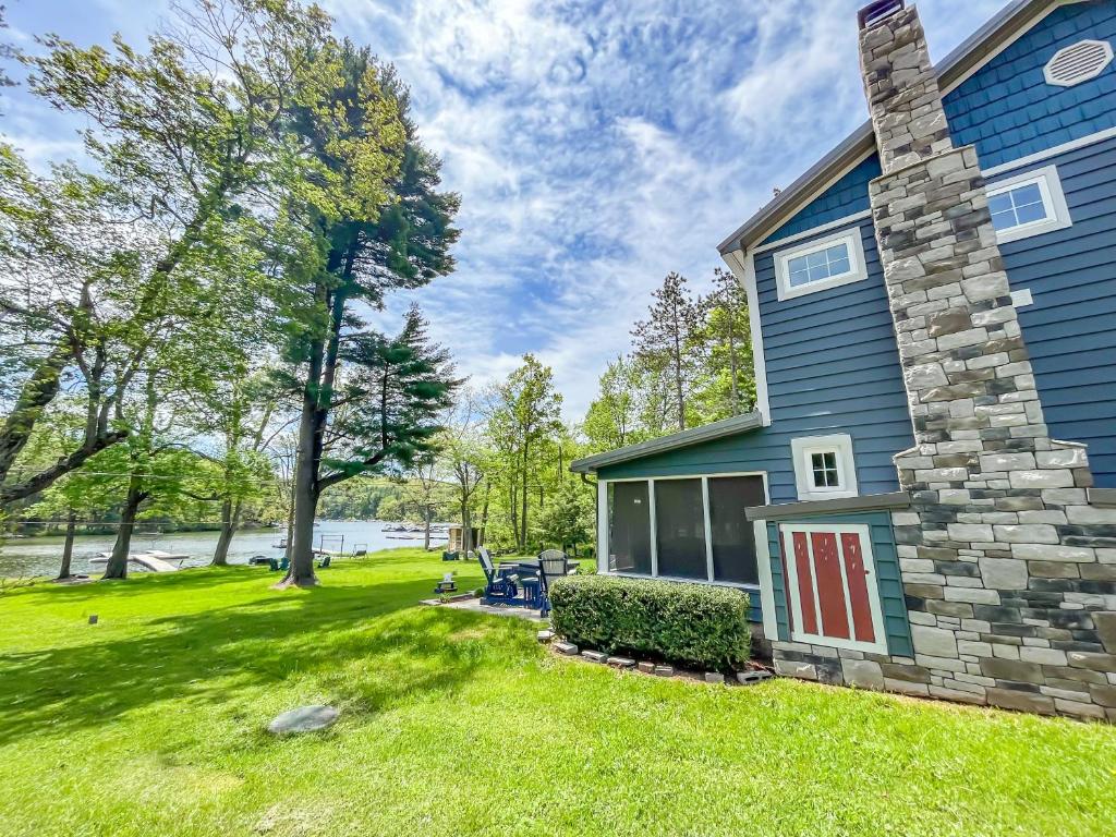 a blue house with a brick chimney and a yard at Adorable Lakefront Cottage with Hot Tub and Dock Pet friendly in Swanton