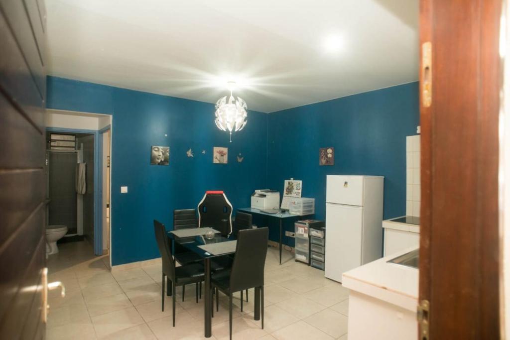 - une cuisine avec des murs bleus, une table et des chaises dans l'établissement Maison de l'ébène Pas, à Cayenne