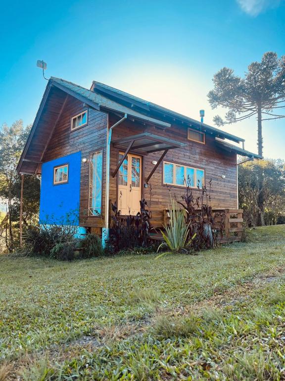 una pequeña casa de madera con puerta azul en Casa Violeta, en Urubici