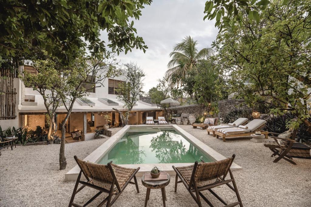 een zwembad in een tuin met 2 stoelen en een bank bij Casa Kacaya in Espita