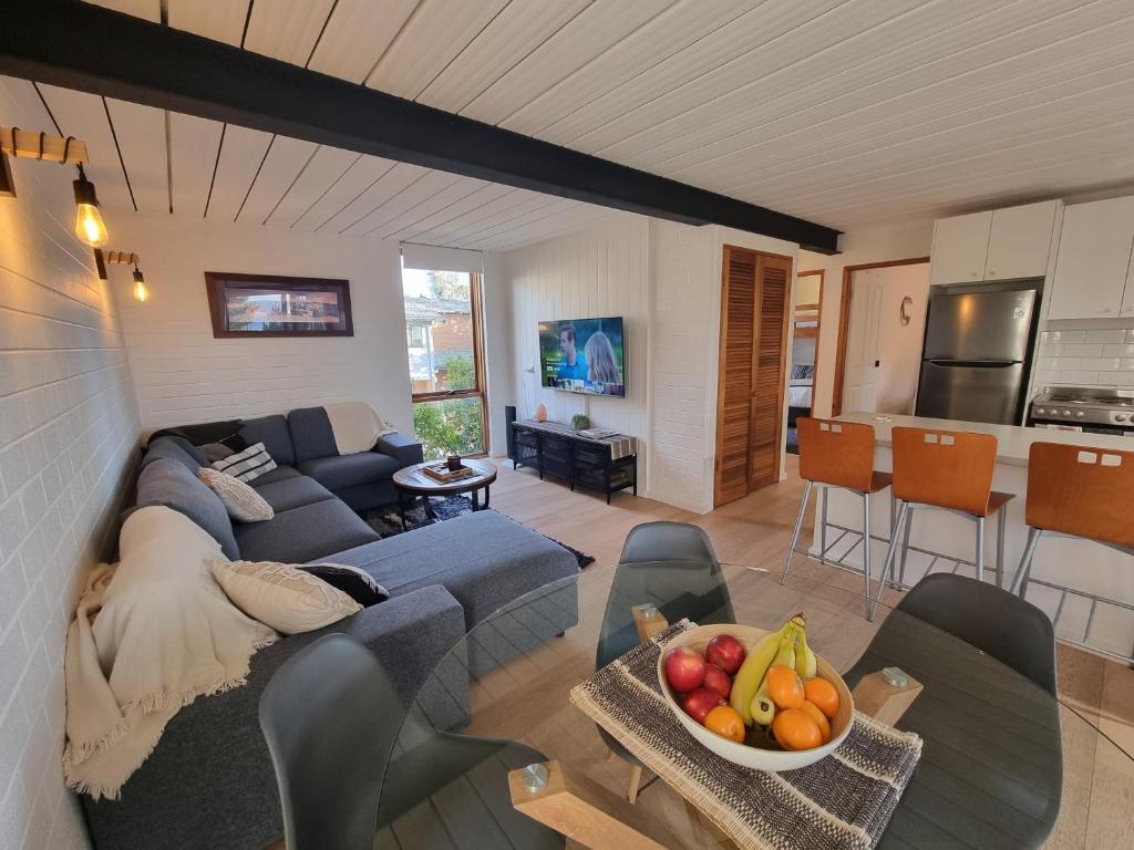 a living room with a couch and a table with a bowl of fruit at *The Hideaway* Lake Views/Bike Storage/Smart Home/Free WiFi in Jindabyne
