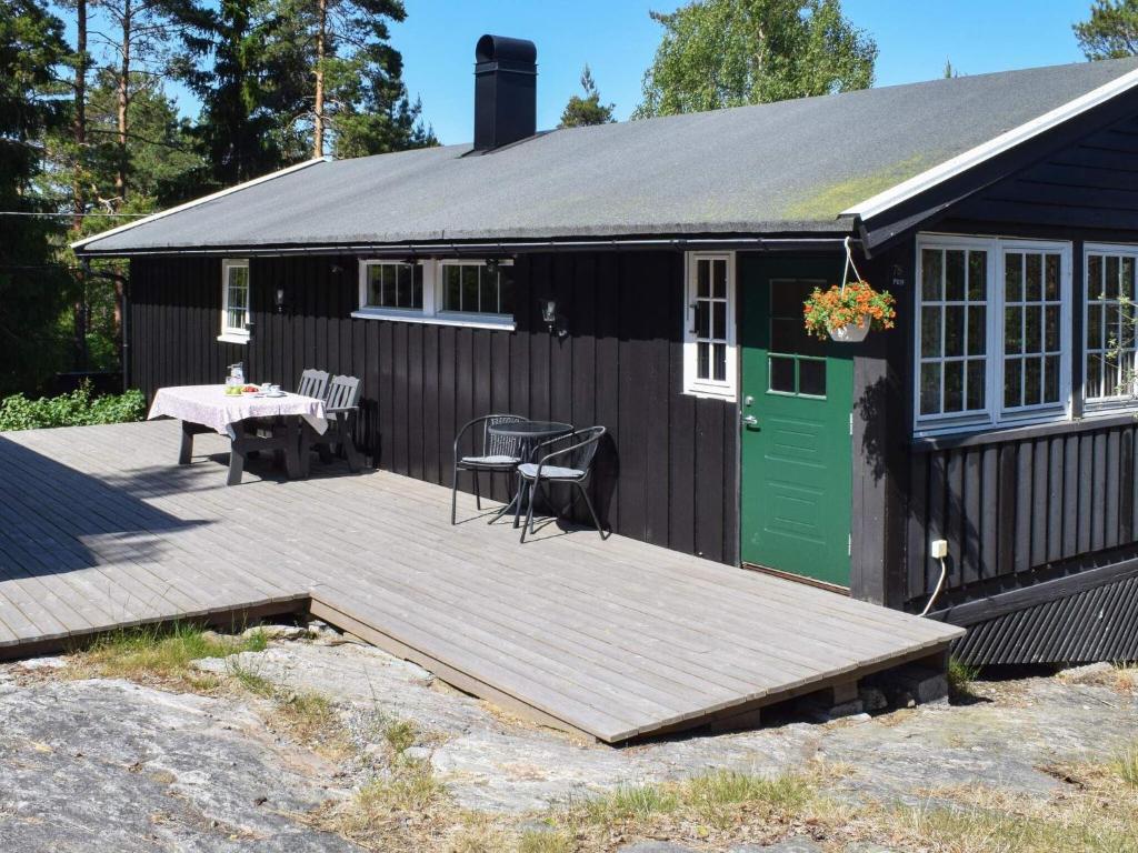 ein kleines schwarzes Haus mit einer Holzterrasse und einem Tisch in der Unterkunft Holiday home Halden IV in Halden