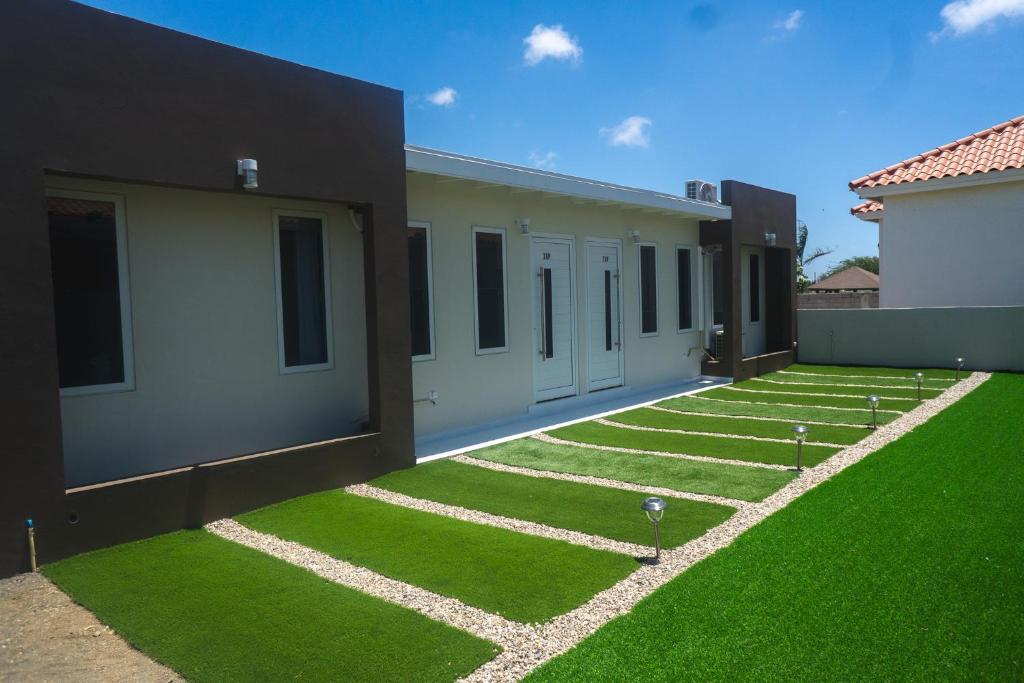 a yard with green grass next to a building at Pavia's Centerpoint Oasis in Oranjestad