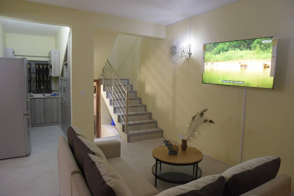 een woonkamer met een bank en een tv aan de muur bij Private home in Flic en Flac - quiet location in Flic-en-Flac
