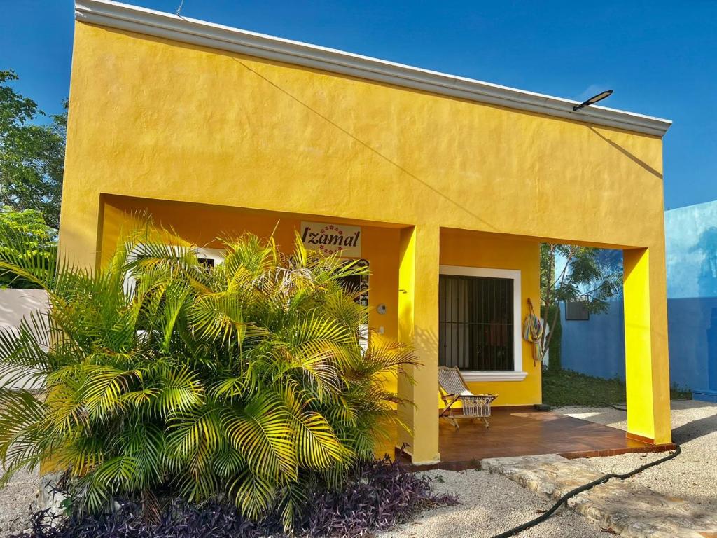 a yellow building with a porch and a palm tree at VILLA DEL CIELO TIXPEHUAL in Tixpehual