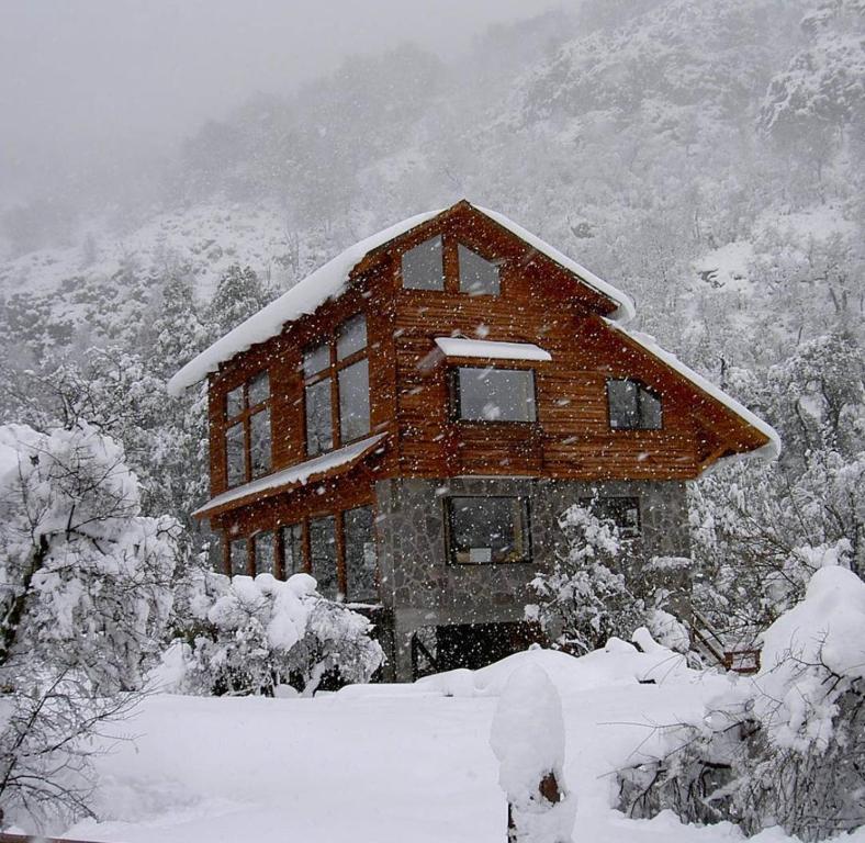 una casa está cubierta de nieve en las montañas en Cabañas Borde Rio Las Trancas, en Nevados de Chillán