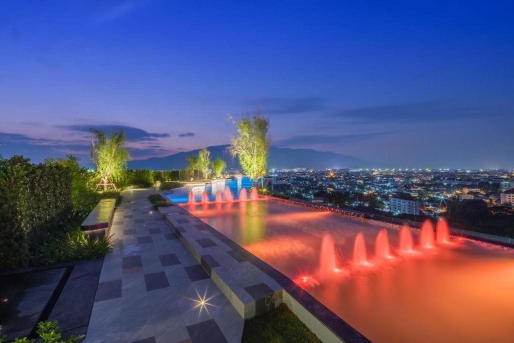a view of a fountain in the water at night at The Astra Sky River Chiangmai_Sky pool_Old City in Chiang Mai