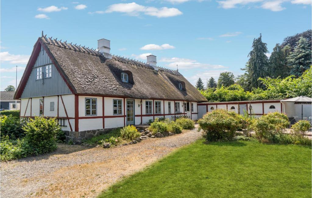 an old white and red house with a yard at 3 Bedroom Awesome Home In Bog By in Bogø By
