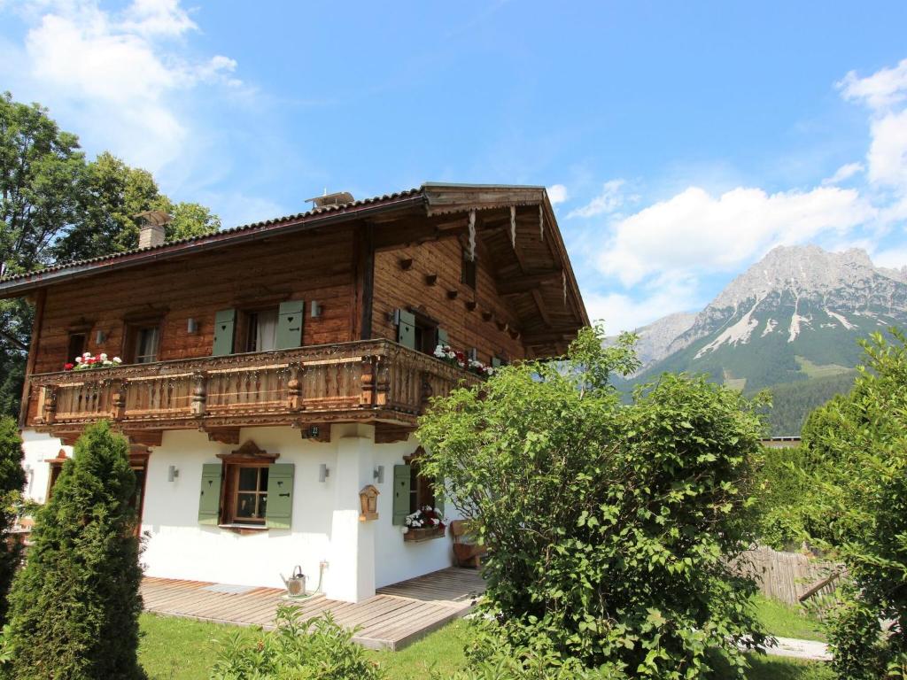 a large wooden house with a mountain in the background at Detached holiday home in Ellmau near the ski lift in Ellmau