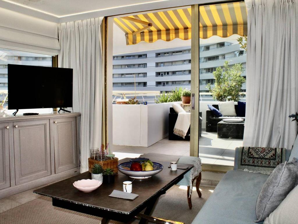 un salon avec une télévision et une table dans l'établissement Superbe appartement climatisé avec terrasse et jardin à Villeneuve Loubet Plage - FR-1-252A-106, à Villeneuve-Loubet