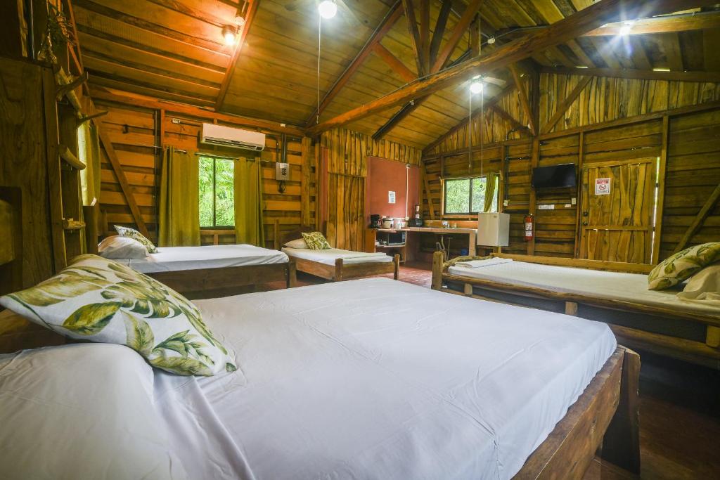 Canto del Tucán Lodge and Farm في غولفيتو: غرفة نوم بسريرين في كابينة خشبية