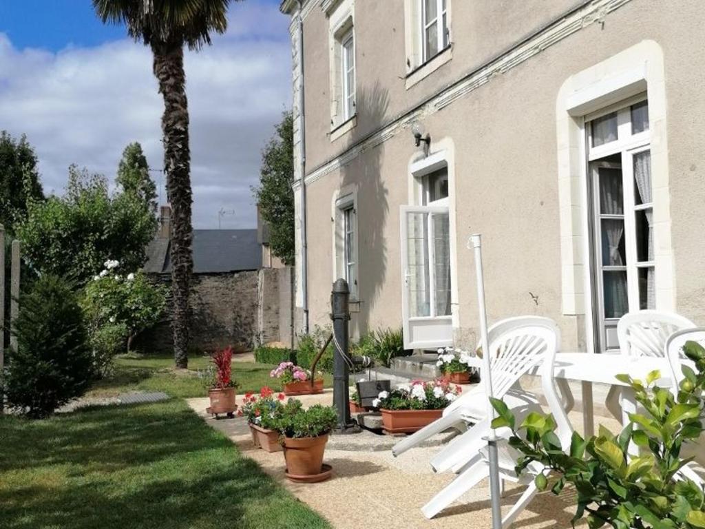 una casa con sillas blancas y una palmera en Guestroom Renazé, 1 pièce, 2 personnes - FR-1-600-229, en Congrier