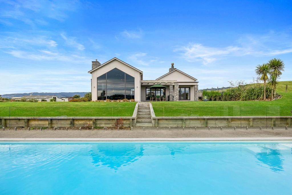 uma casa com piscina em frente a uma casa em Sandhill Beach House - Te Horo Holiday Home em Te Horo