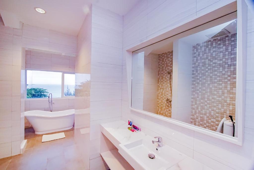 ein Badezimmer mit einer Badewanne, einem Waschbecken und einem Spiegel in der Unterkunft Dafam Resort Belitung in Tanjungbinga