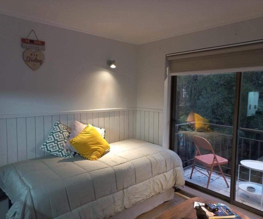 a bedroom with a bed with a yellow pillow on it at Parque suizo, Pucon in Pucón