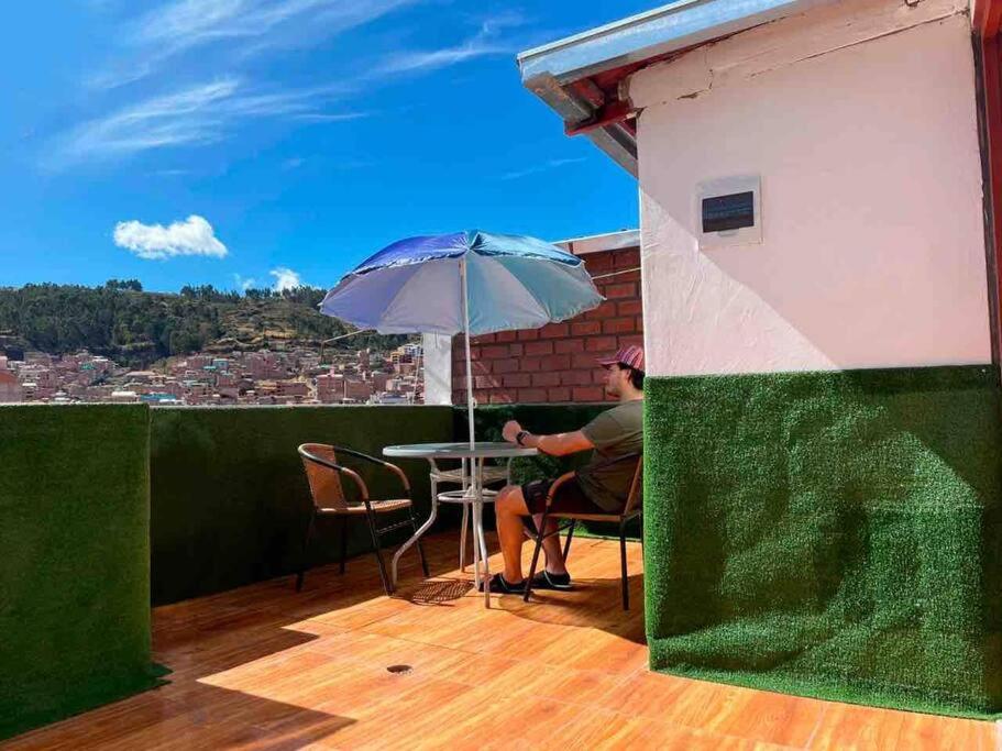a man sitting at a table with an umbrella on a balcony at Departamento con vista panoramica in Cusco