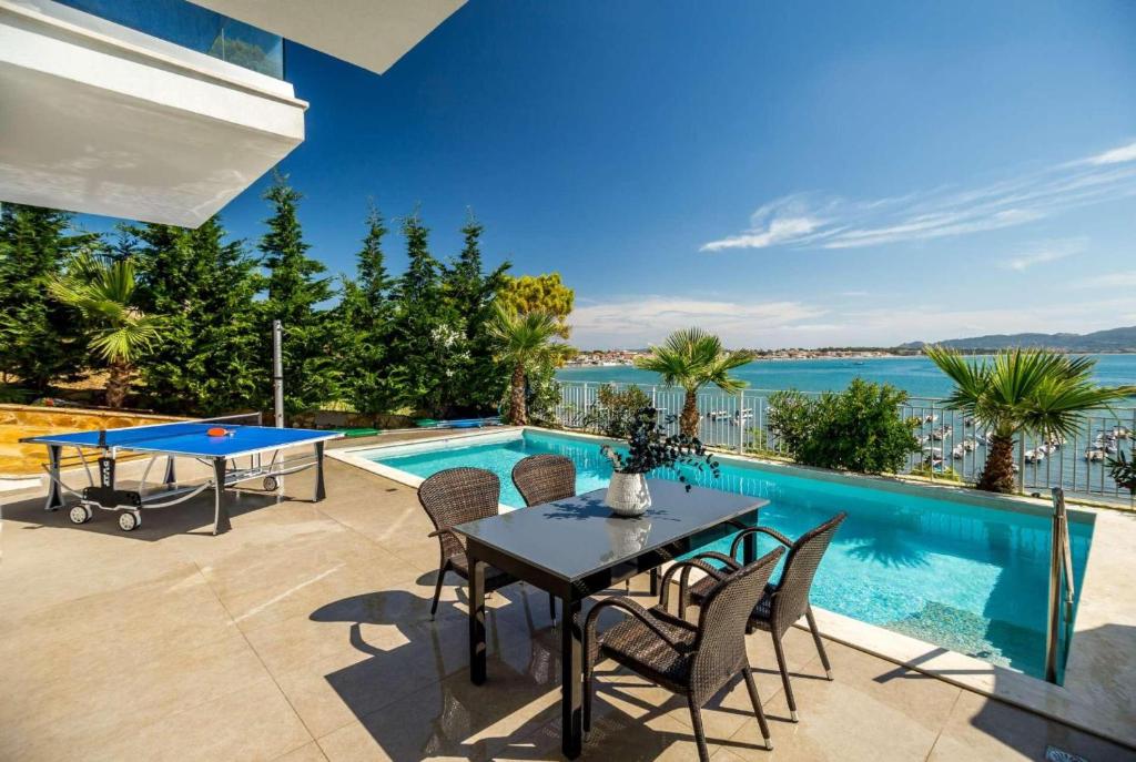 a patio with a table and chairs and a pool at Agios Sostis Harbour View in Laganas
