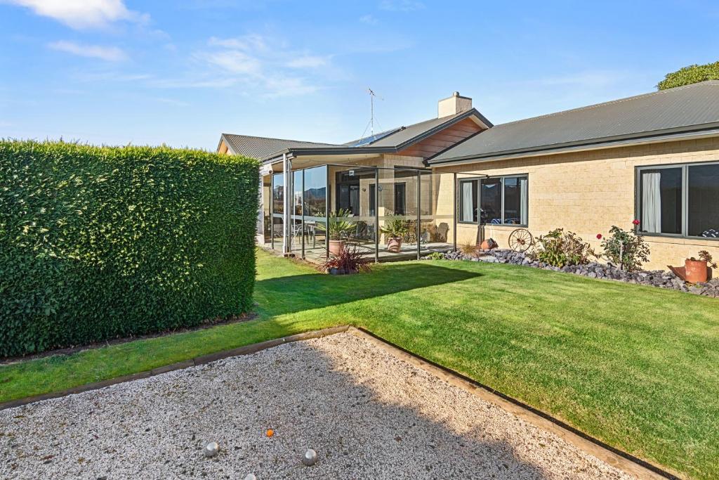 a house with a hedge in front of a yard at Selmes Sanctuary - Blenheim Holiday Home in Blenheim