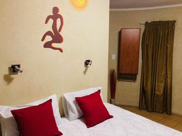 1 dormitorio con 1 cama con 2 almohadas rojas en Eagle Crest Executive Lodge, en Edenvale