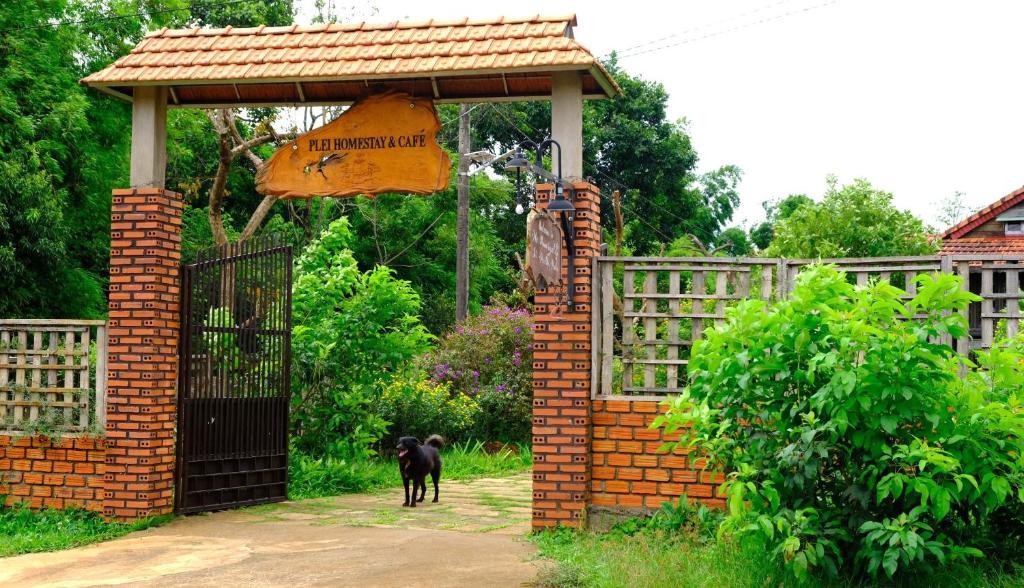 Czarny pies stojący przed bramą w obiekcie Plei Homestay & Café w mieście Pleiku