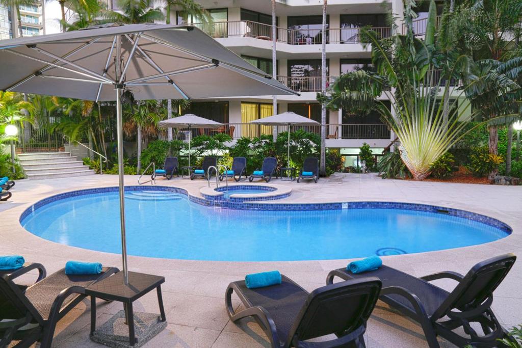 黃金海岸的住宿－Genesis Apartments by Gold Coast Premium，一个带躺椅和遮阳伞的游泳池