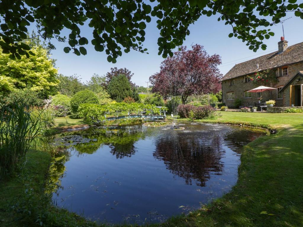 a garden with a pond in front of a building at Lower Court Byre in Kinsham