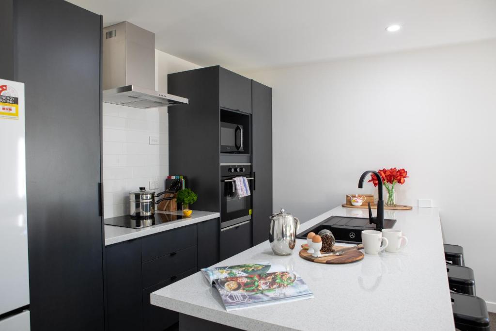 a kitchen with black cabinets and a white counter top at Twin Camellias in Rotorua