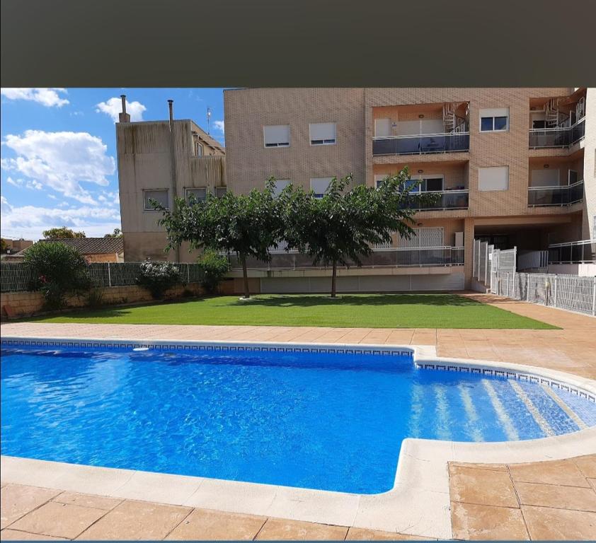 una gran piscina frente a un edificio en 1 bajo con 2 Terrazas piscina y jardin, en Deltebre