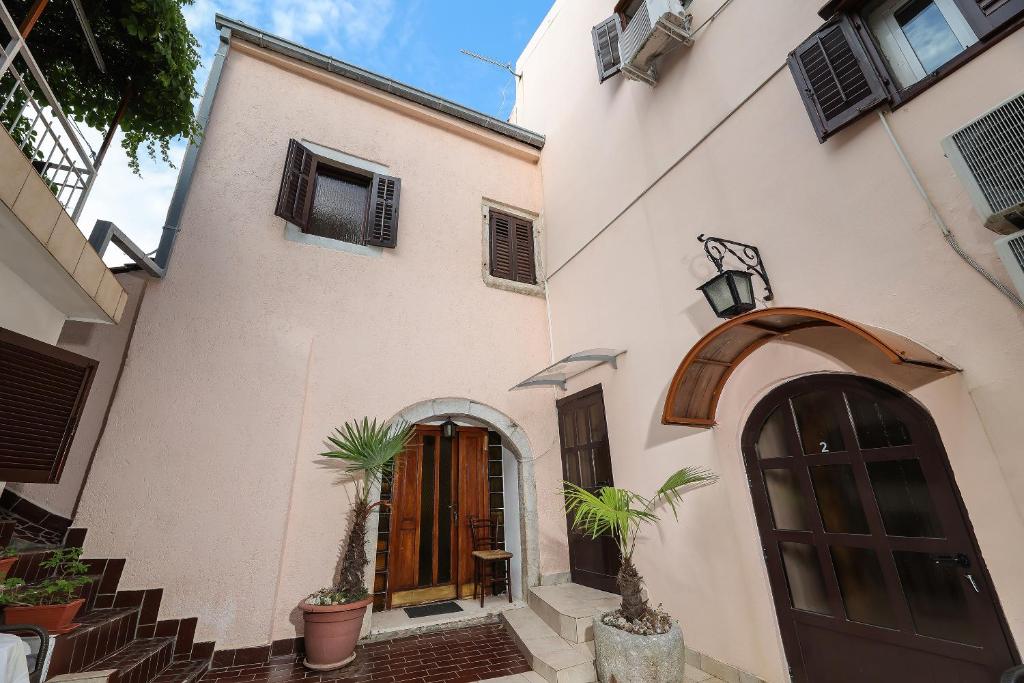 a white building with a door and some potted plants at Casa di Nives in Krk