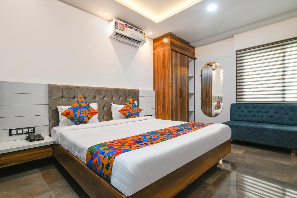 ein Schlafzimmer mit einem großen Bett und einem blauen Sofa in der Unterkunft FabHotel Stay Well in Indore
