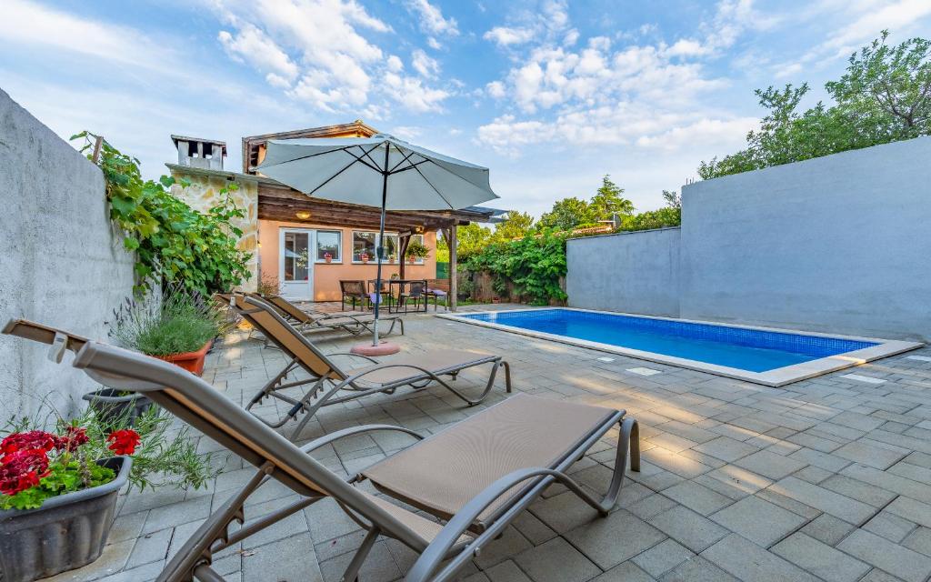 um pátio com cadeiras, um guarda-sol e uma piscina em Villa Iness Medulin em Medulin