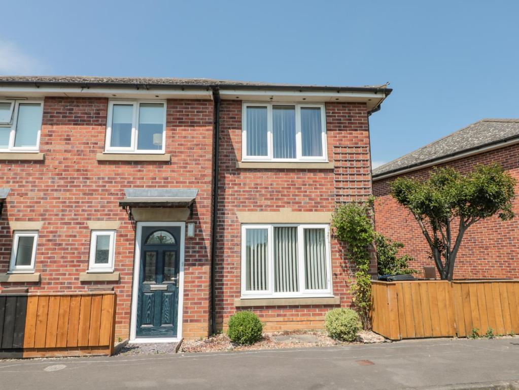 a red brick house with a black door at Sutton Court in Thirsk