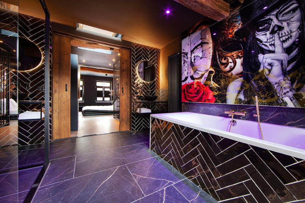 uma casa de banho com banheira e pinturas na parede em Chambers Roermond em Roermond