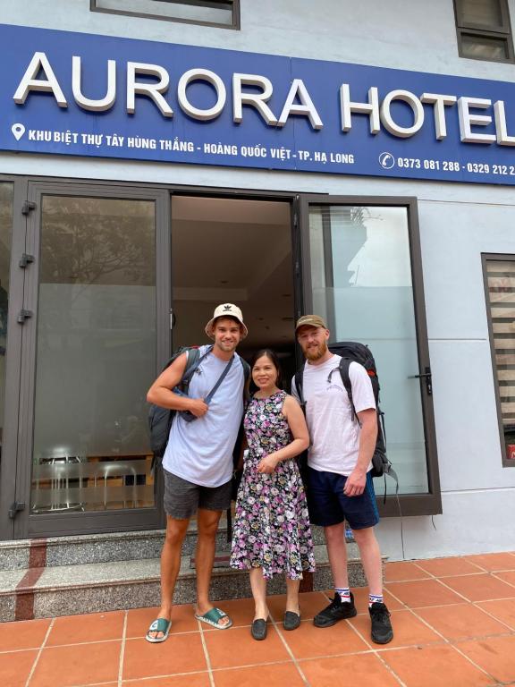 een groep van drie personen die voor een hotel staan bij Aurora halong in Ha Long