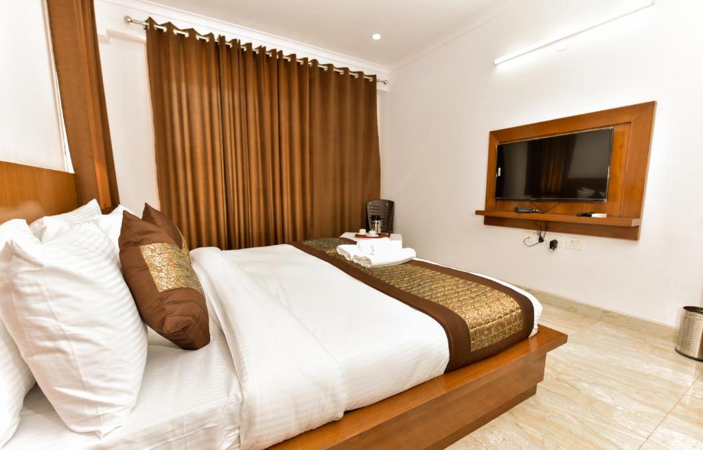 ein Schlafzimmer mit einem großen Bett und einem TV in der Unterkunft Hotel Shivaye Residency, Gurgaon 