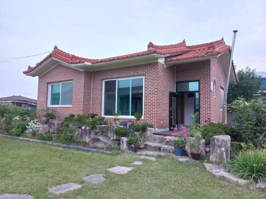 une maison en briques rouges avec un jardin en face de celle-ci dans l'établissement Breeze in May Pension, à Gyeongju