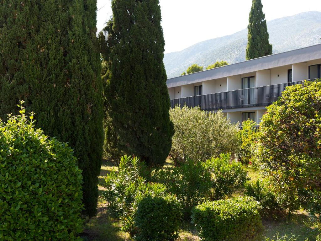 a building surrounded by trees and bushes at Bluesun Holiday Village Bonaca - Full Board Plus in Bol