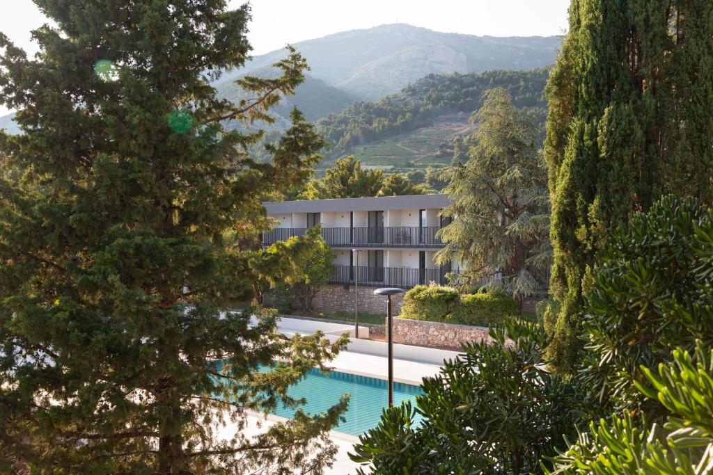 an apartment building with a swimming pool and mountains in the background at Bluesun Holiday Village Bonaca - Full Board Plus in Bol