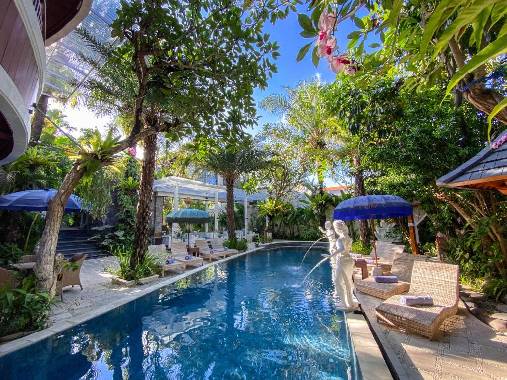 a pool at a resort with chairs and umbrellas at The Bali Dream Villa & Resort Echo Beach Canggu in Canggu