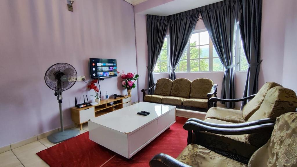 un soggiorno con divano e tavolo di A ONE Holiday Apartment a Tanah Rata