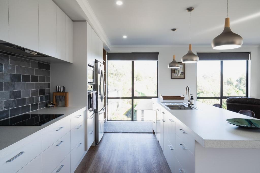 a kitchen with white cabinets and a large window at Modern family friendly getaway in Dunedin
