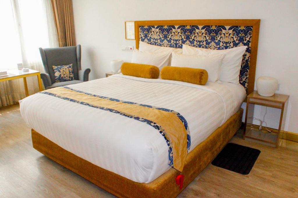 Schlafzimmer mit einem großen Bett mit einem Kopfteil aus Holz in der Unterkunft Hotel Razmoni Isha Kha International in Dhaka