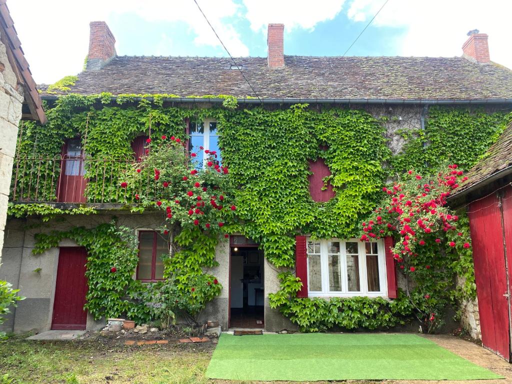 une maison recouverte de lierre avec des portes rouges et des fleurs dans l'établissement CHARMANTE MAISON DE CAMPAGNE DU 17ème siècle à Lilette avec Jacuzzi et proche rivière, à Buxeuil